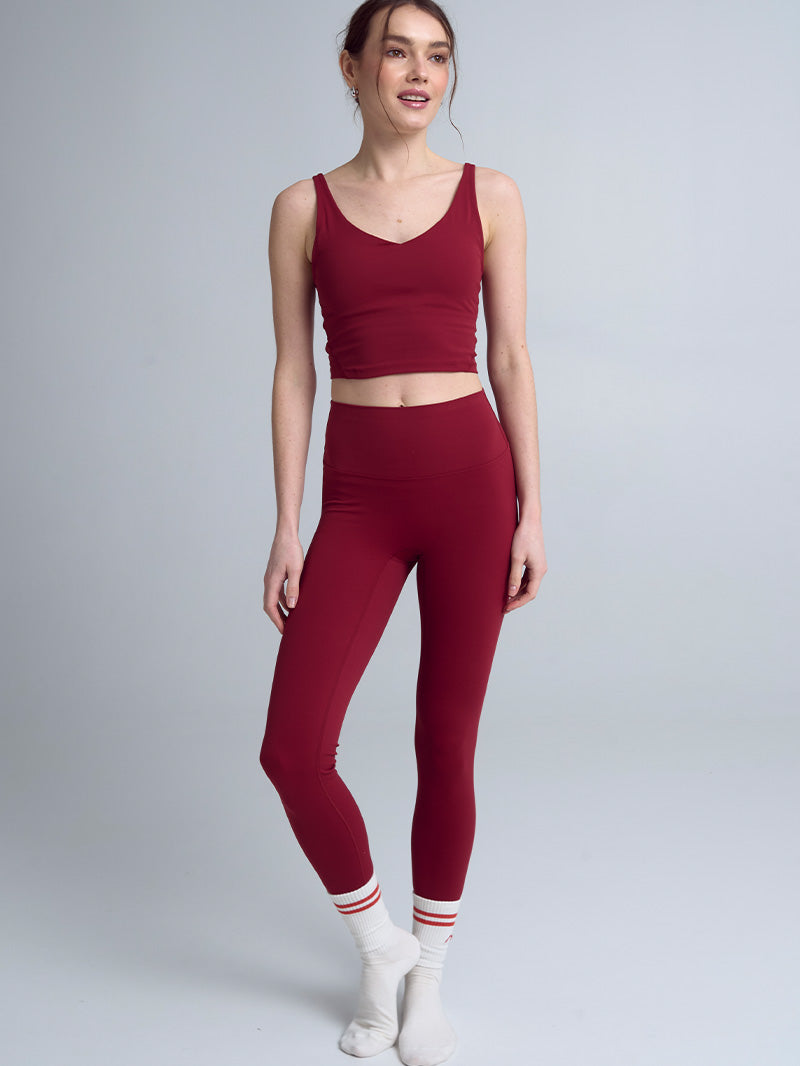 Modelka prezentująca pełną sylwetkę w bordowych legginsach z wysokim stanem i dopasowanym bordowym topie, ukazująca elegancki krój i intensywny kolor Red Wine idealny do jogi.
