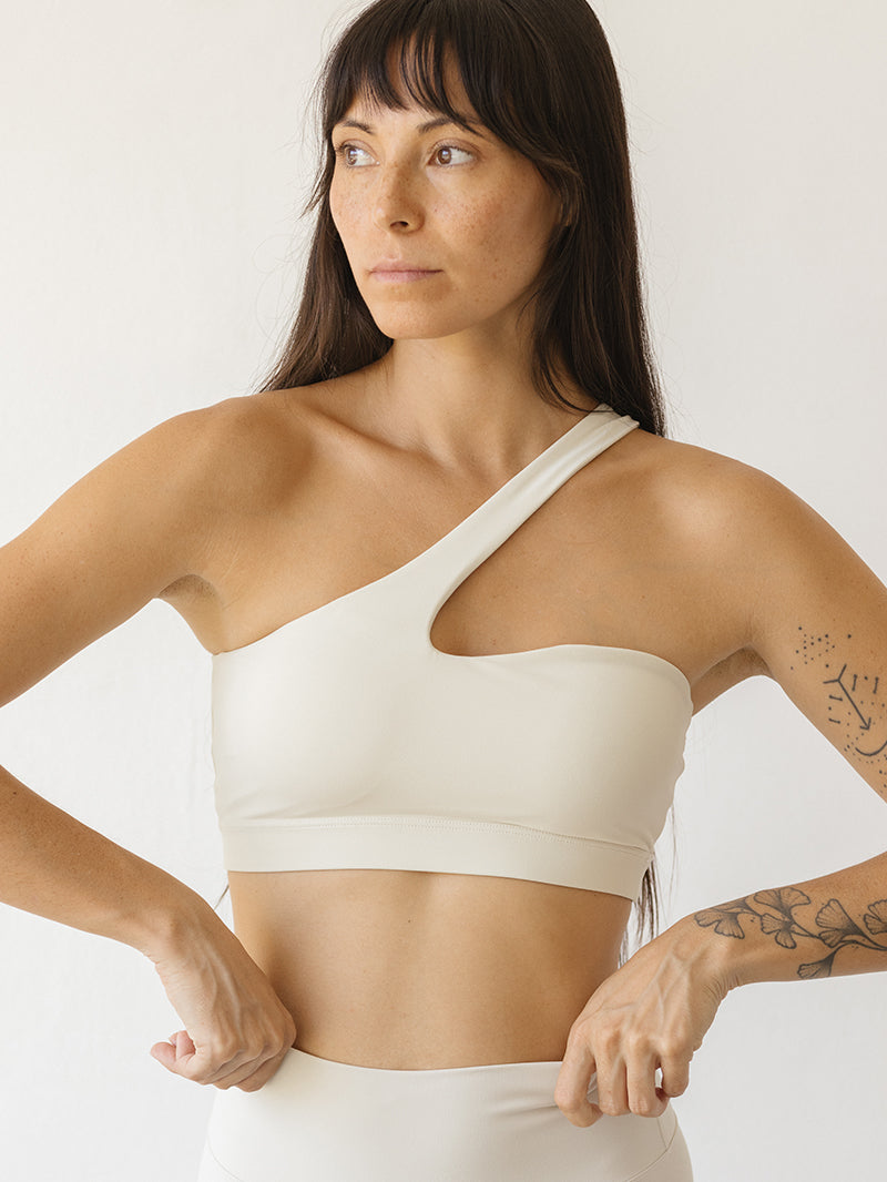 Modelka w białym staniku sportowym i do jogi z ramiączkiem przechodzącym przez środek dekoltu