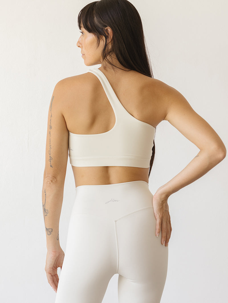Modelka w białym asymetrycznym staniku do jogi Vibe Out i legginsach