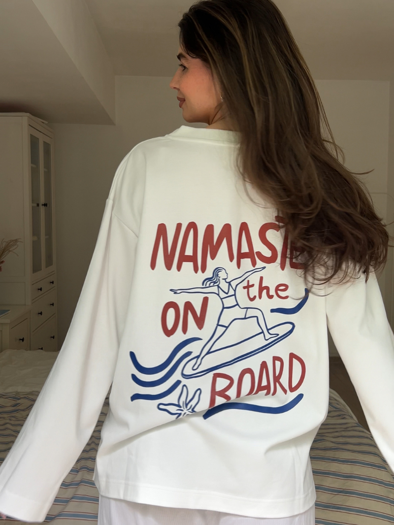 Biała koszulka damska z długimi rękawami o luźnym kroju i z nadrukiem NAMASTE ON the BOARD