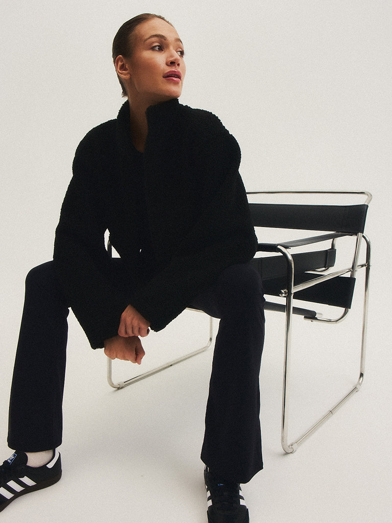 modelka w czarnych spodniach flare na krześle