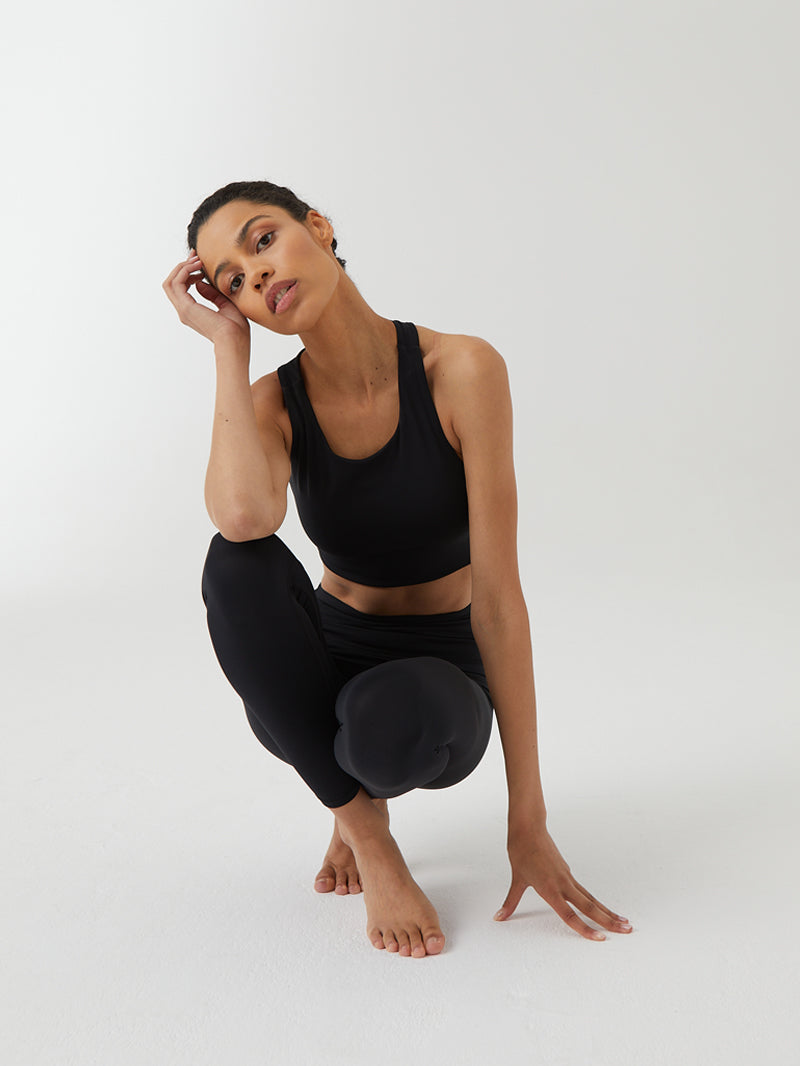 kucająca modelka w czarnym staniku do jogi z wycięciem na plecach Goddess