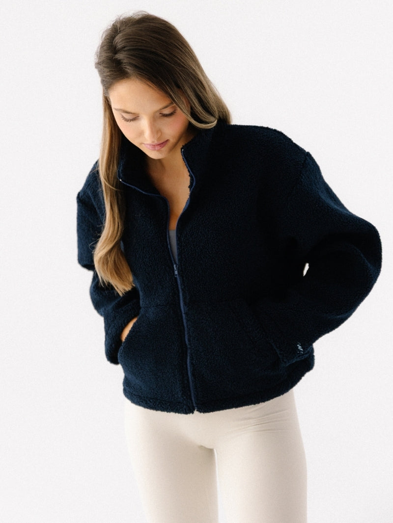 Ciepła bluza polarowa z wysokim kołnierzem w odcieniu granatu. Dopasowanie relaxed fit i miękki w dotyku polar sherpa. Rozpinana i z kieszeniami