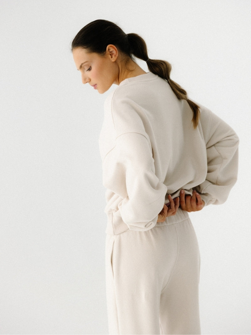 Kremowe bawełniane spodnie dresowe z serii KIND — luźny krój, wysoki stan z elastycznym paskiem i lekko zwężane nogawki ze ściągaczem