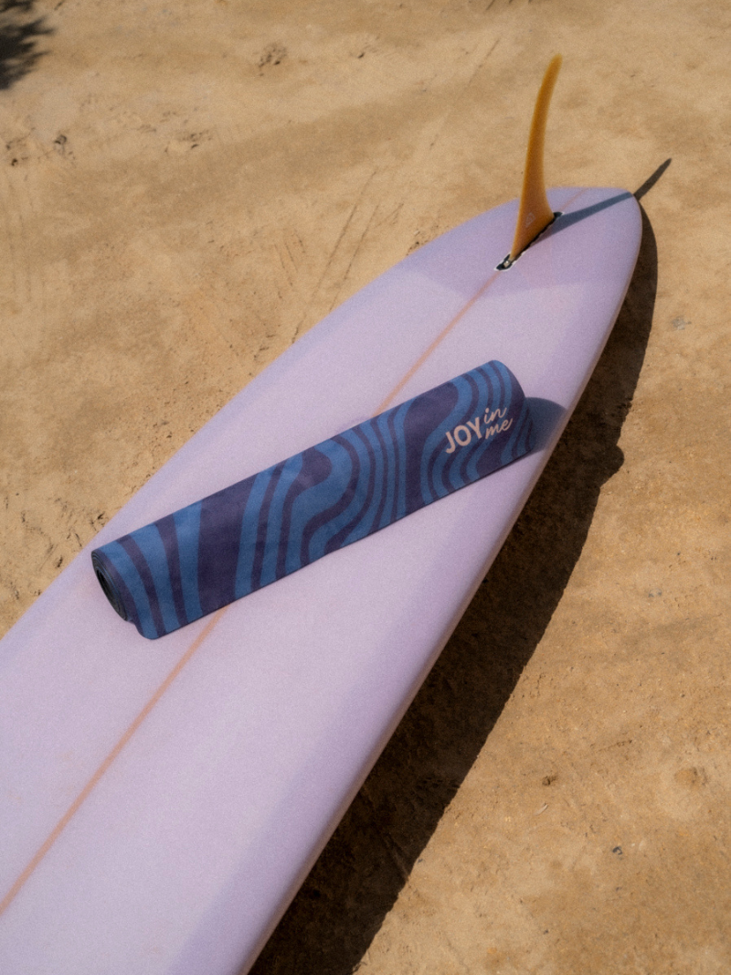 Niebieska antypoślizgowa mata do ćwiczeń jogi 3 mm z grafiką surferki - zrolowana mata na plaży