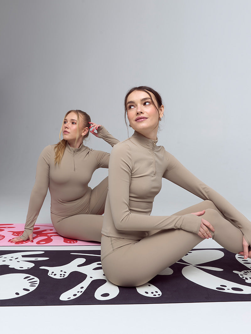 Sportowy beżowy longsleeve damski z zamkiem Motion - dwie dziewczyny podczas ćwiczeń na macie do jogi