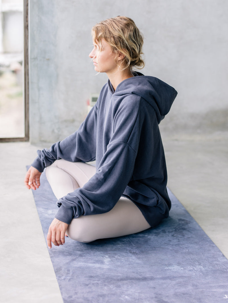 Granatowa kauczukowa mata do jogi z mikrofibrą - joginka podczas pranayamy w luźnej bluzie