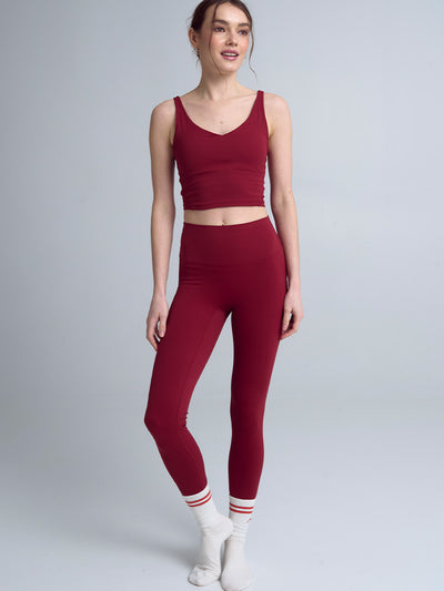 Modelka prezentująca pełną sylwetkę w bordowych legginsach z wysokim stanem i dopasowanym bordowym topie, ukazująca elegancki krój i intensywny kolor Red Wine idealny do jogi.